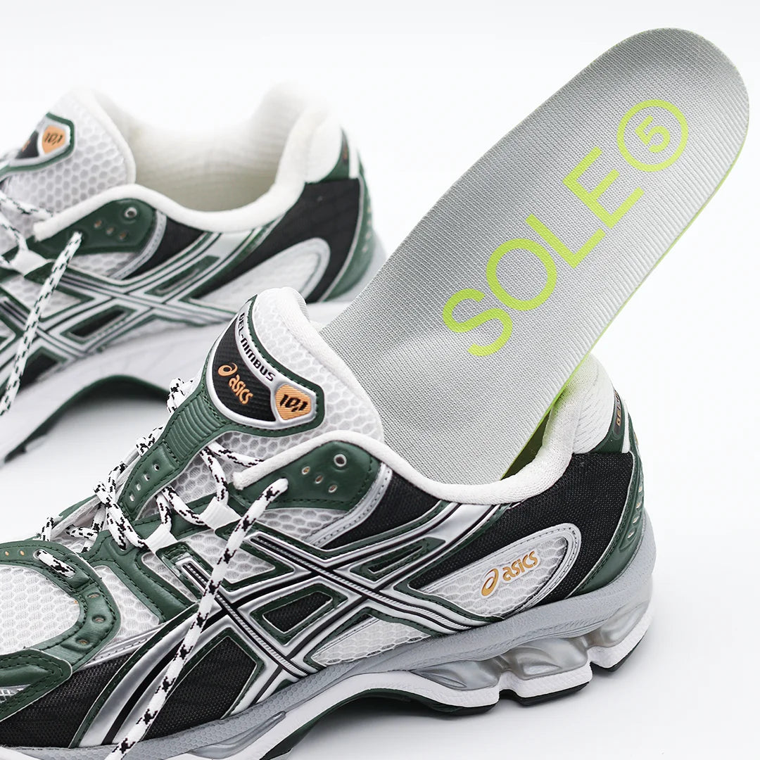 Green and white running shoe with a SOLE5 Orthotic Insole being placed into it