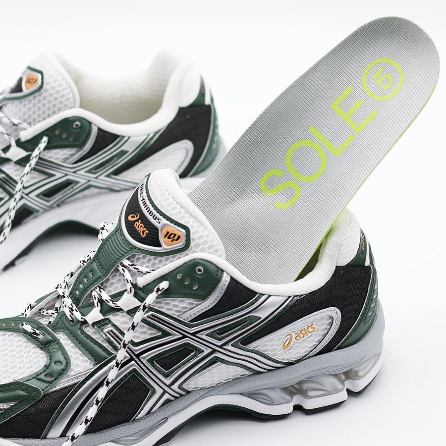 Green and white running shoe with a SOLE5 Orthotic Insole being placed into it