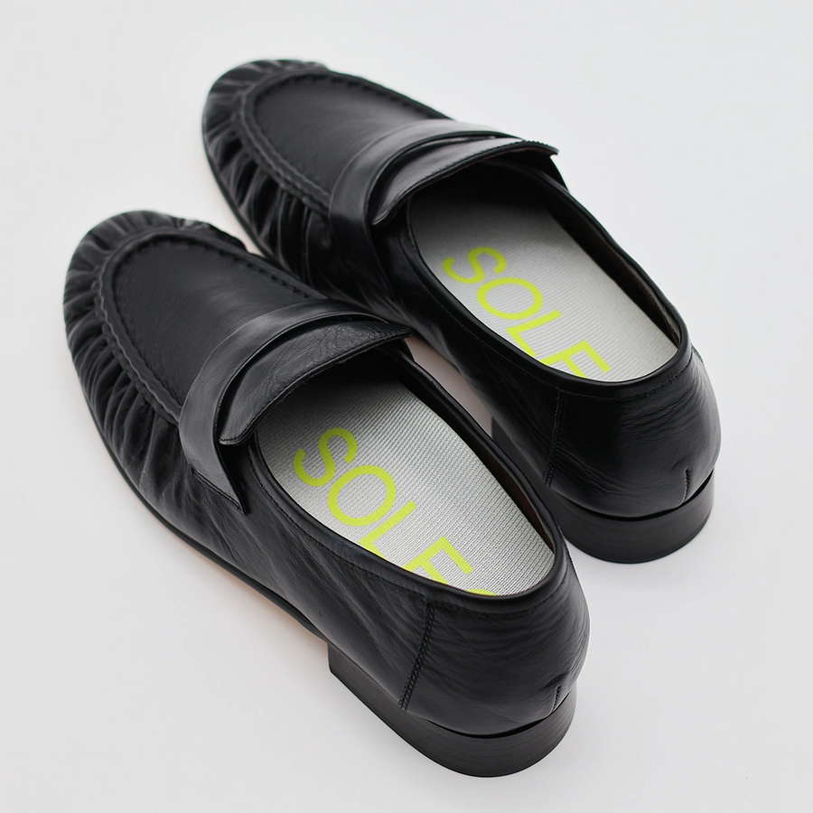 A close up photo of a pair of loafers with a pair of SOLE5 Half Length Orthotic Insoles fitted inside