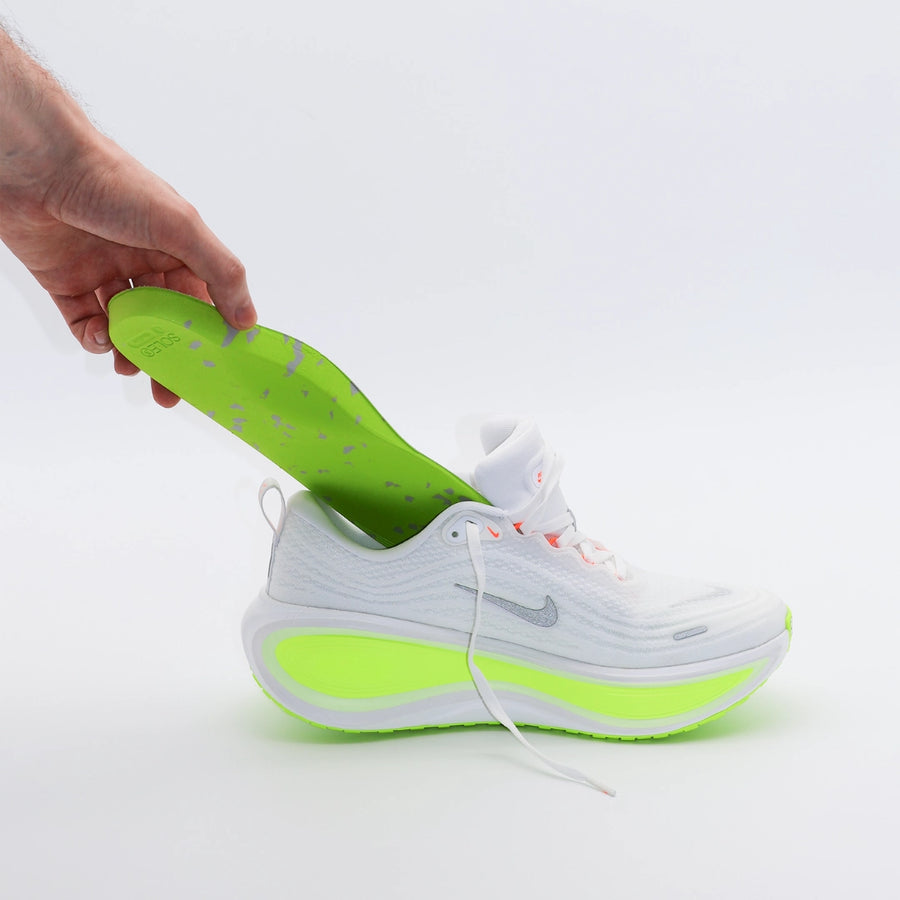 White and green running shoe with a hand placing a SOLE5 Full Length Orthotic Insole inside it
