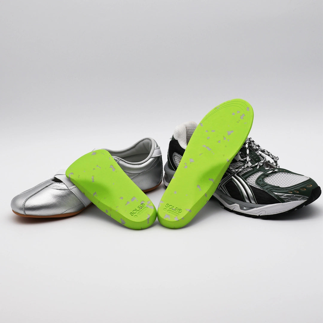 A silver casual shoe & a green athletic shoe with SOLE5 Half Length & Full Length Orthotic Insoles leaning against them. Highlighting the unique green and grey colours.