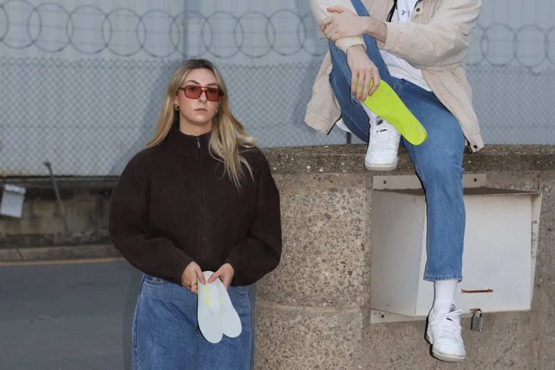 Two people sitting on a ledge with a neutral background