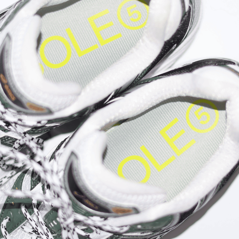 Close-up of white sneakers with 'SOLE5' orthotics branding on a white background