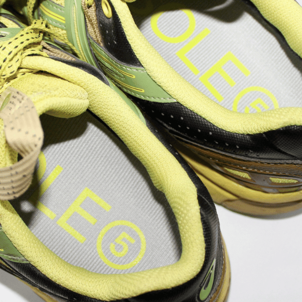 Close-up of a pair of green and ywllow sneakers with visible SOLE5 orthotic insoles, highlighting SOLE5 logo.