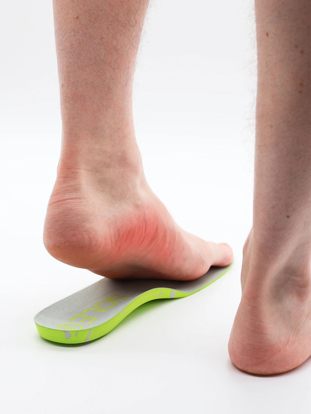 Person wearing a SOLE5 orthotic with a red area on their arch indicating arch pain  on a white background