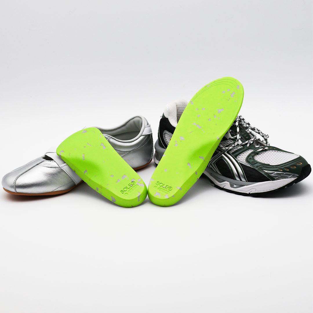 A silver casual shoe & a green athletic shoe with SOLE5 Half Length & Full Length Orthotic Insoles leaning against them. Highlighting the unique green and grey colours.