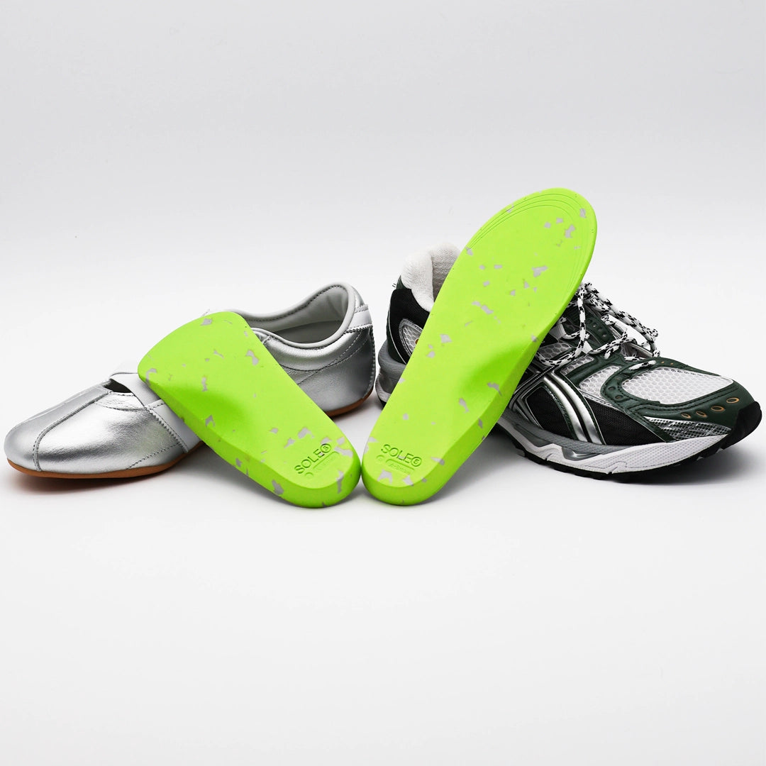 A silver casual shoe & a green athletic shoe with SOLE5 Half Length & Full Length Orthotic Insoles leaning against them. Highlighting the unique green and grey colours.