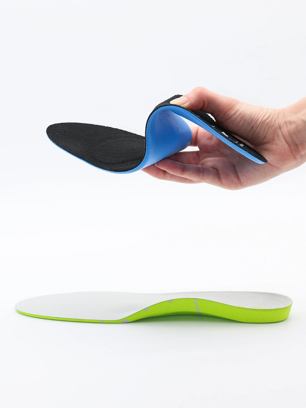 Hand holding a generic blue and black shoe insole that's flimsy with no support.
