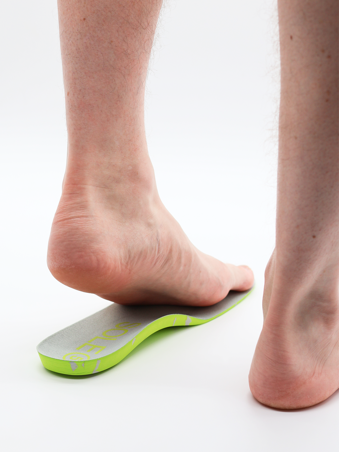 A foot being placed onto a SOLE5 Full Length insole. It is against a bright white background giving the image a medical vibe.